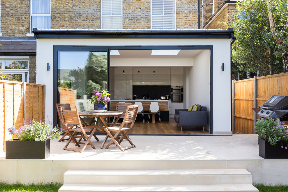 Mid-sized contemporary backyard patio in London with tile.