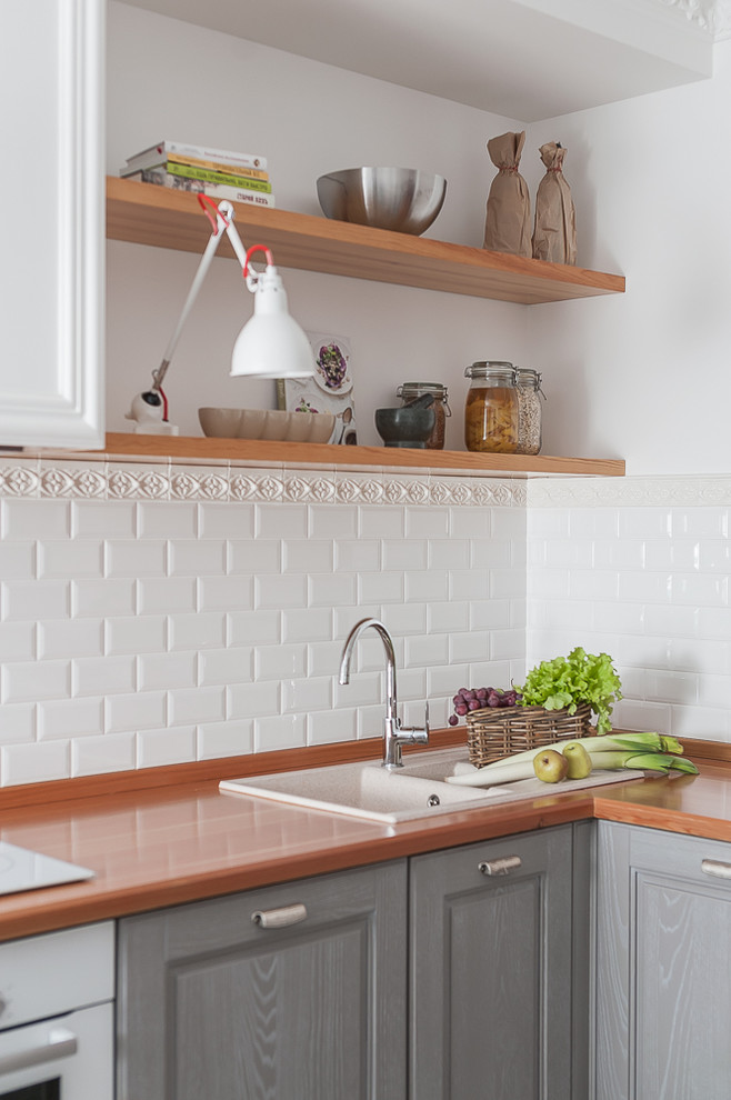This is an example of a small scandinavian l-shaped eat-in kitchen in Other with an undermount sink, raised-panel cabinets, grey cabinets, wood benchtops, white splashback, subway tile splashback, white appliances, ceramic floors, grey floor and yellow benchtop.