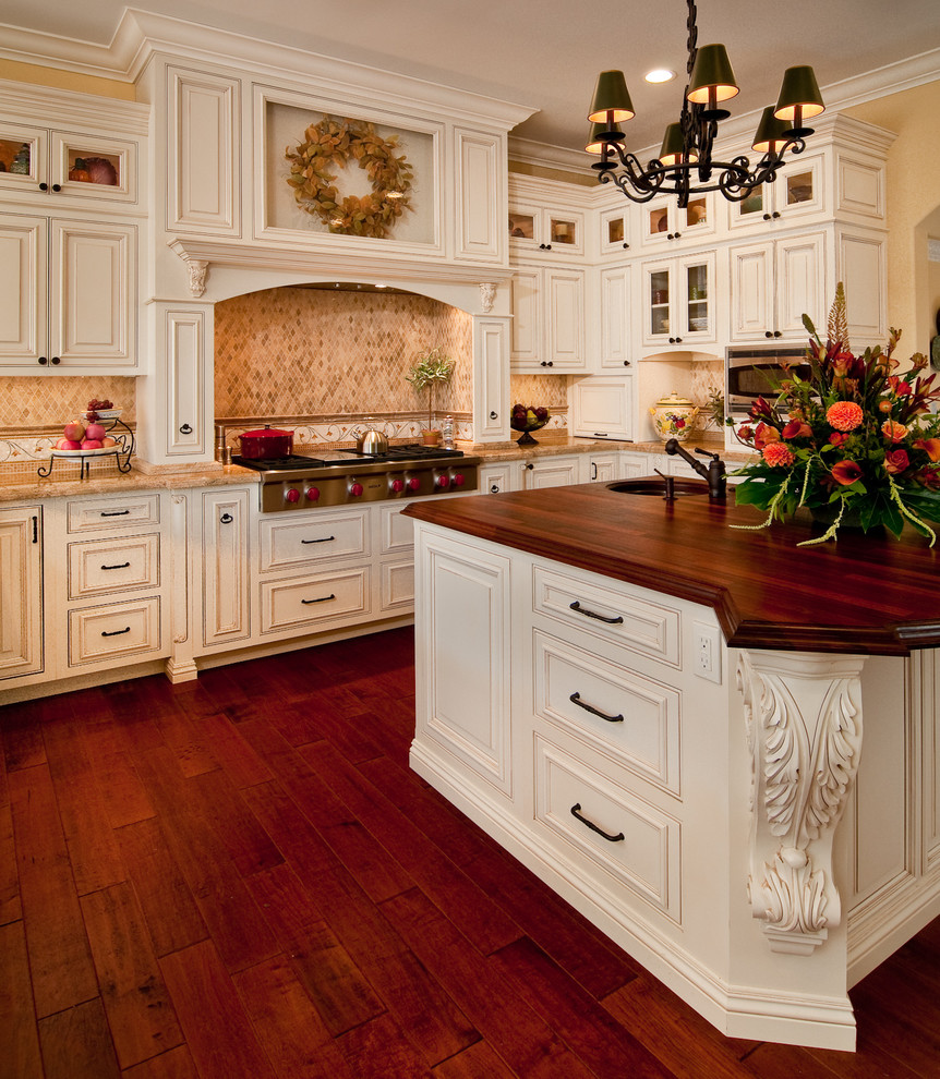 This is an example of a traditional kitchen in Other with beaded inset cabinets and wood benchtops.