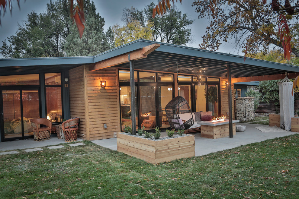 Midcentury backyard patio in Denver with a fire feature, concrete slab and a roof extension.