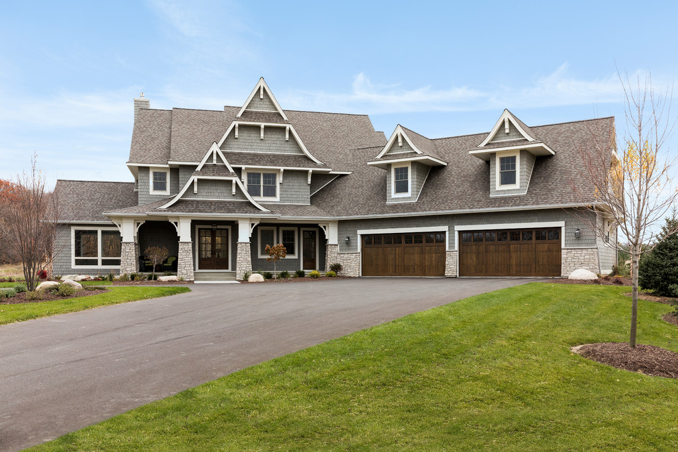Large beach style two-storey grey house exterior in Minneapolis with a gable roof and a shingle roof.