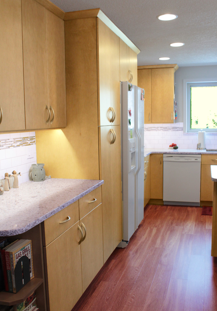 Kitchen - transitional u-shaped kitchen idea in Boise with an undermount sink, granite countertops, white backsplash, subway tile backsplash, white appliances, flat-panel cabinets, light wood cabinets and a peninsula