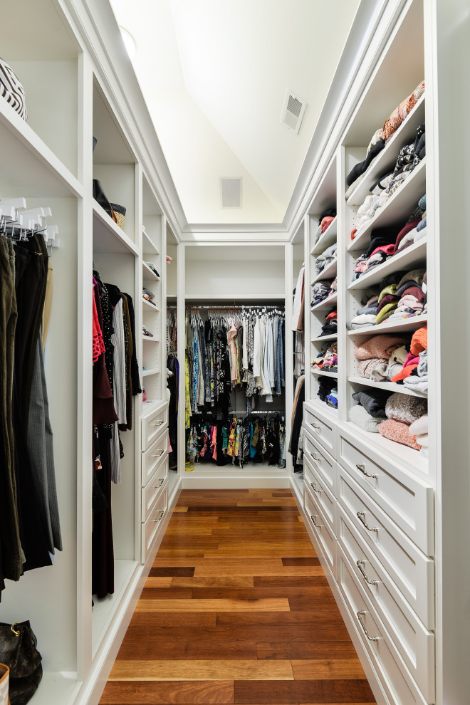 Inspiration for a transitional gender-neutral walk-in wardrobe in Philadelphia with shaker cabinets, white cabinets, medium hardwood floors, brown floor and vaulted.