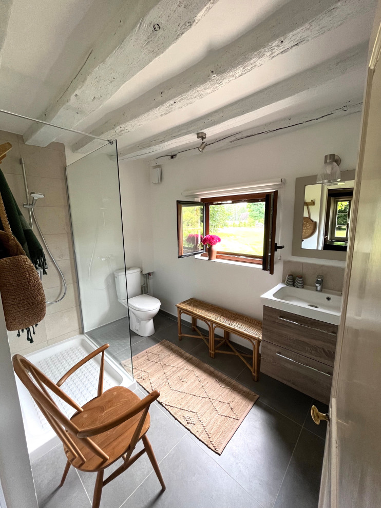 Foto på ett mellanstort lantligt badrum med dusch, med en kantlös dusch, en toalettstol med hel cisternkåpa, beige kakel, keramikplattor, klinkergolv i keramik, ett nedsänkt handfat och grått golv