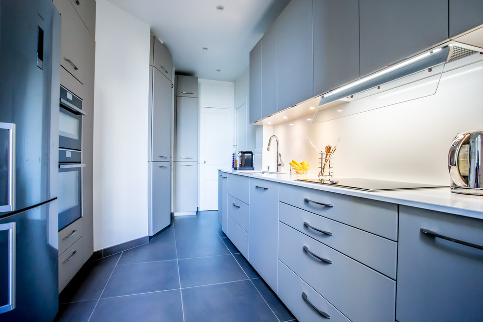 This is an example of a mid-sized contemporary galley separate kitchen in Paris with an integrated sink, beaded inset cabinets, white cabinets, quartzite benchtops, white splashback, stainless steel appliances, ceramic floors, no island and grey floor.