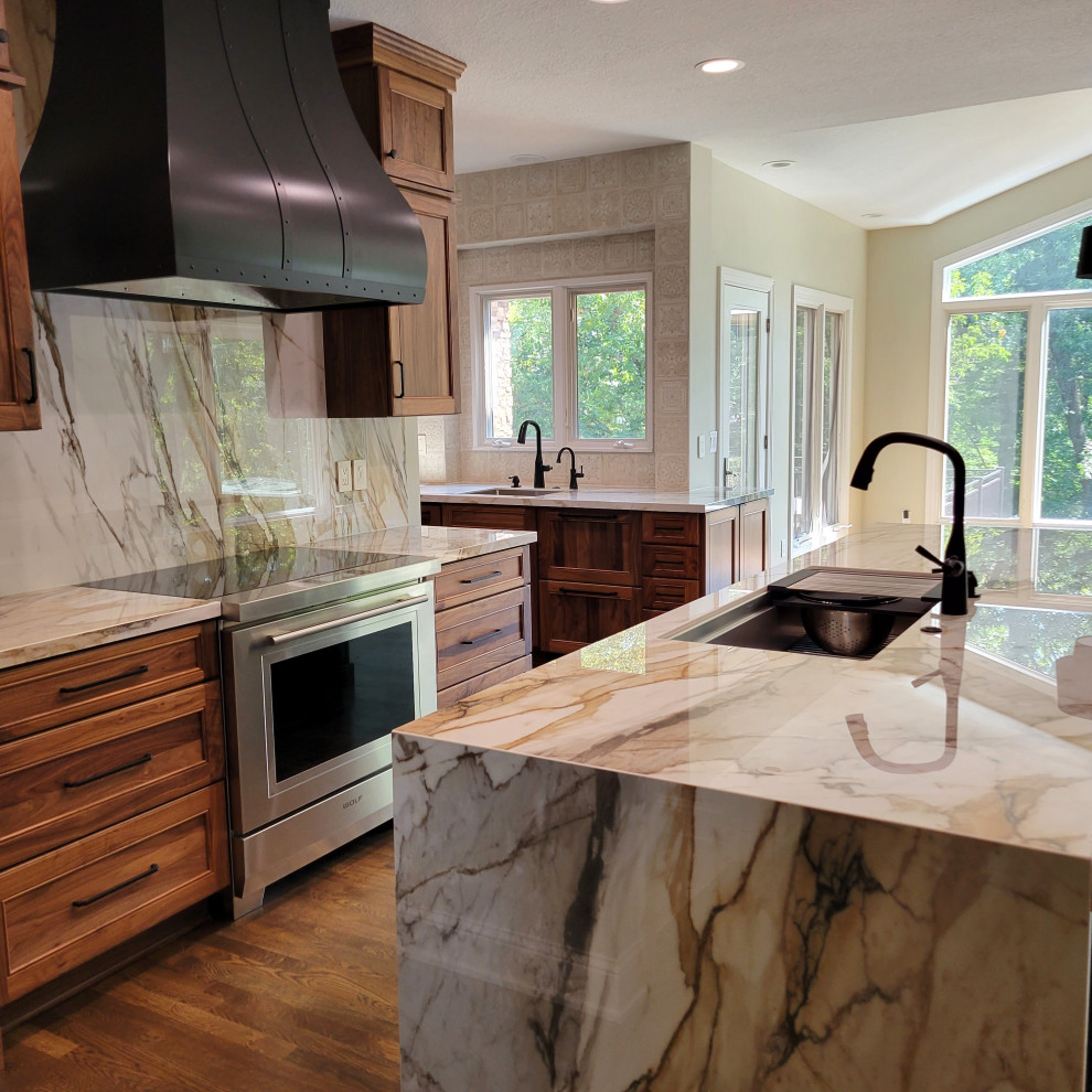 Large transitional medium tone wood floor and brown floor kitchen photo with an undermount sink, recessed-panel cabinets, medium tone wood cabinets, multicolored backsplash, stainless steel appliances, an island and multicolored countertops