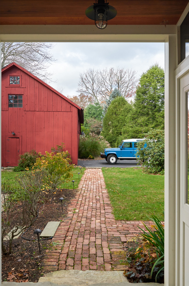 Example of a large farmhouse dark wood floor and brown floor mudroom design in New York with white walls and a green front door
