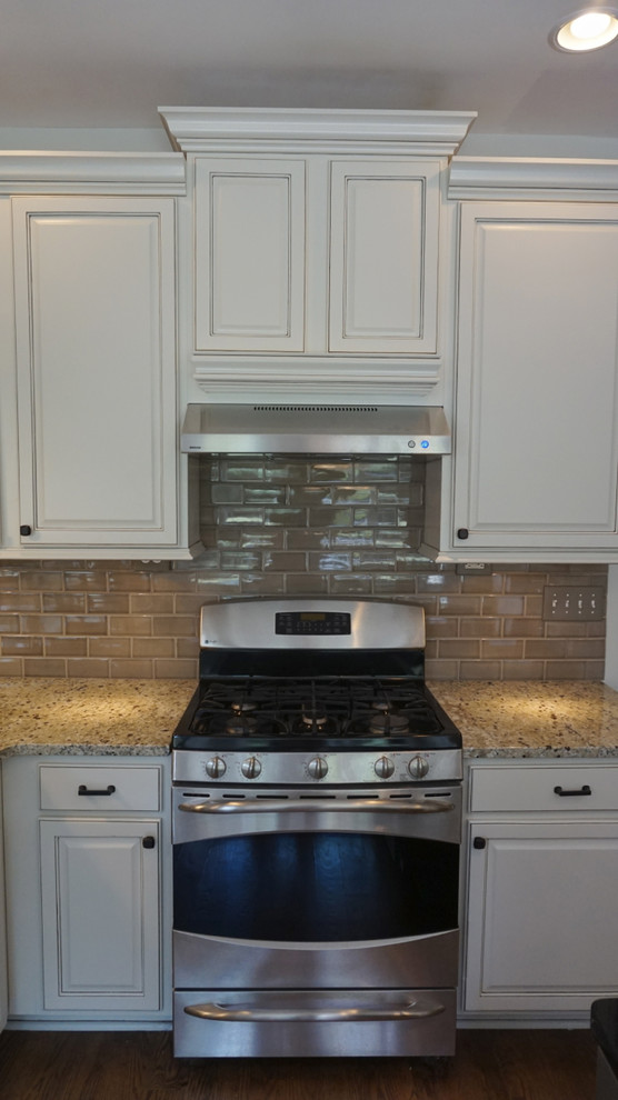 Eat-in kitchen - large transitional u-shaped medium tone wood floor eat-in kitchen idea in Atlanta with an undermount sink, raised-panel cabinets, white cabinets, granite countertops, gray backsplash, ceramic backsplash, stainless steel appliances and an island