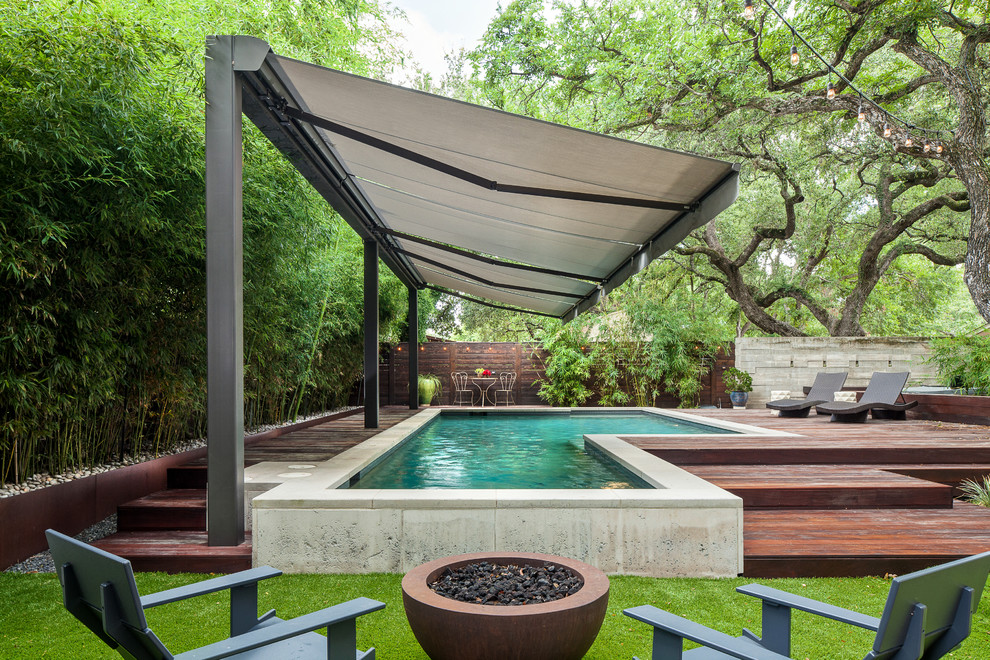 Photo of a mid-sized modern backyard custom-shaped pool in Austin with decking.