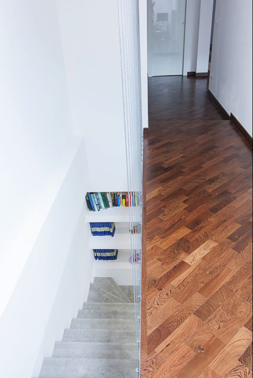 Photo of a mid-sized contemporary tile l-shaped staircase in Bologna with tile risers and cable railing.