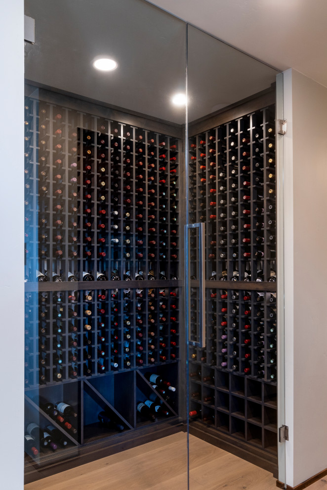 Mid-sized midcentury wine cellar in Other with light hardwood floors and storage racks.
