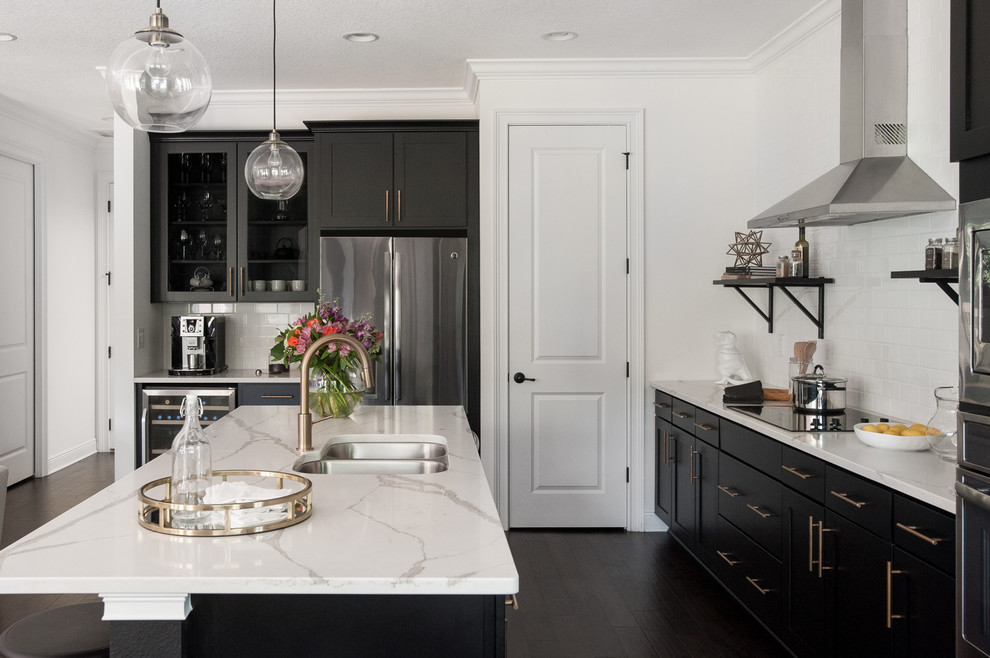 This is an example of a large transitional l-shaped open plan kitchen in Tampa with a double-bowl sink, shaker cabinets, black cabinets, quartzite benchtops, white splashback, subway tile splashback, stainless steel appliances, dark hardwood floors, with island and brown floor.