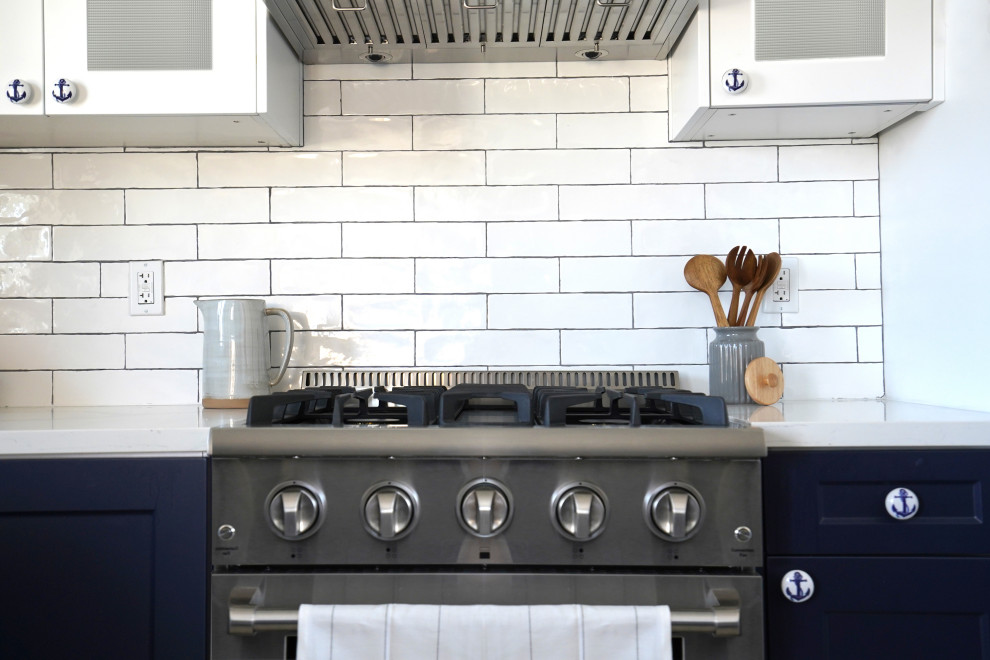 Exempel på ett mellanstort maritimt vit vitt kök, med en rustik diskho, skåp i shakerstil, blå skåp, bänkskiva i kvarts, vitt stänkskydd, stänkskydd i tunnelbanekakel, rostfria vitvaror, klinkergolv i keramik, en köksö och flerfärgat golv