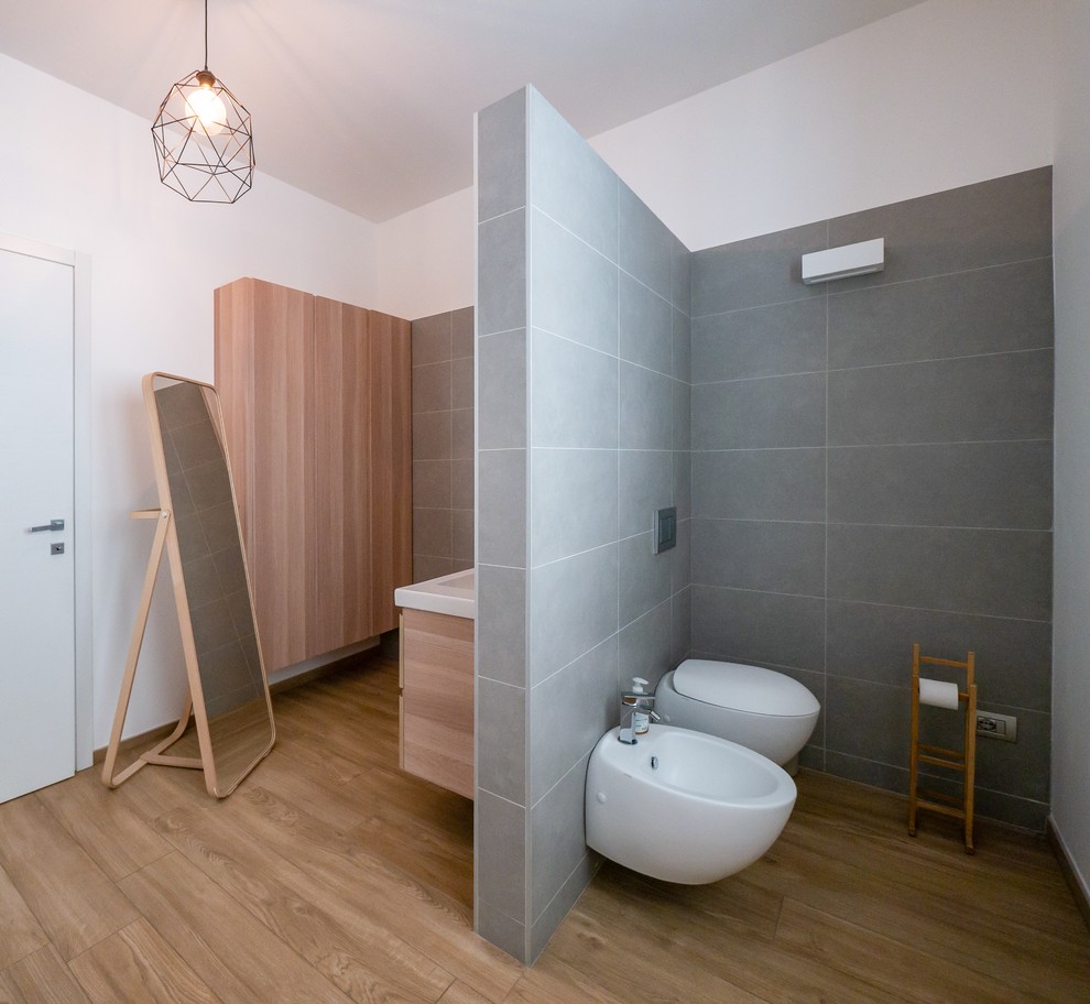 Design ideas for a large scandinavian powder room in Milan with flat-panel cabinets, light wood cabinets, a wall-mount toilet, gray tile, porcelain tile, white walls, porcelain floors, a console sink, wood benchtops, beige floor and beige benchtops.