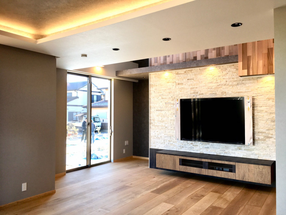 Diseño de salón abierto moderno con paredes grises, suelo de madera clara, televisor colgado en la pared, suelo marrón, papel pintado y papel pintado