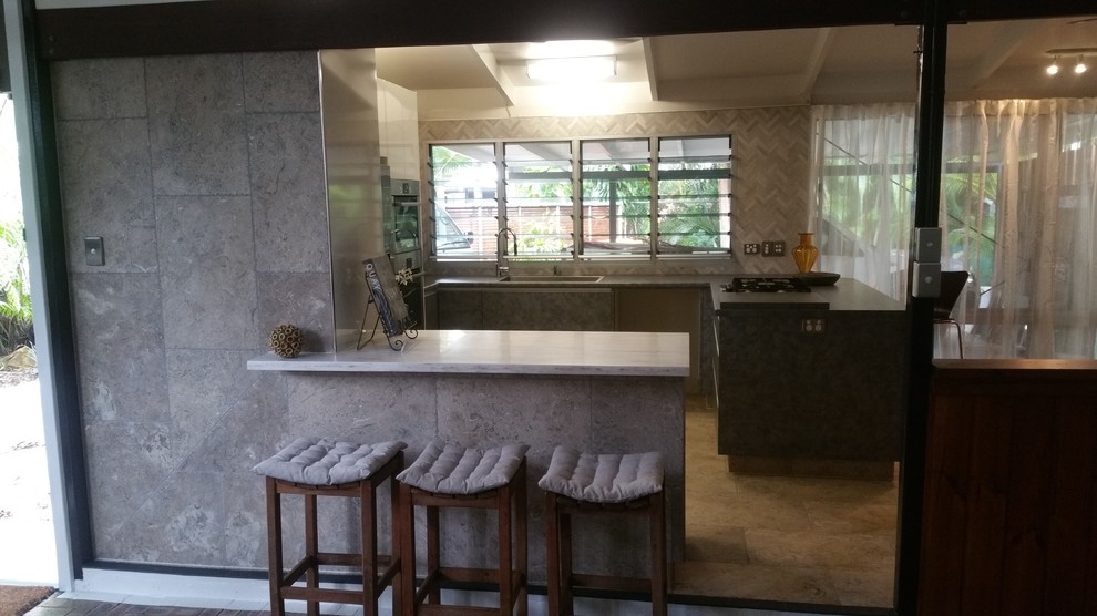 Mid-sized eclectic u-shaped home design in Darwin with a drop-in sink, flat-panel cabinets, blue cabinets, solid surface benchtops, grey splashback, mosaic tile splashback, stainless steel appliances, slate floors and multiple islands.