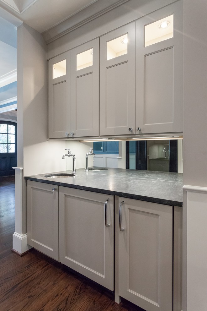 Traditional single-wall kitchen pantry in DC Metro with an undermount sink, recessed-panel cabinets, beige cabinets, mirror splashback, medium hardwood floors, brown floor and black benchtop.