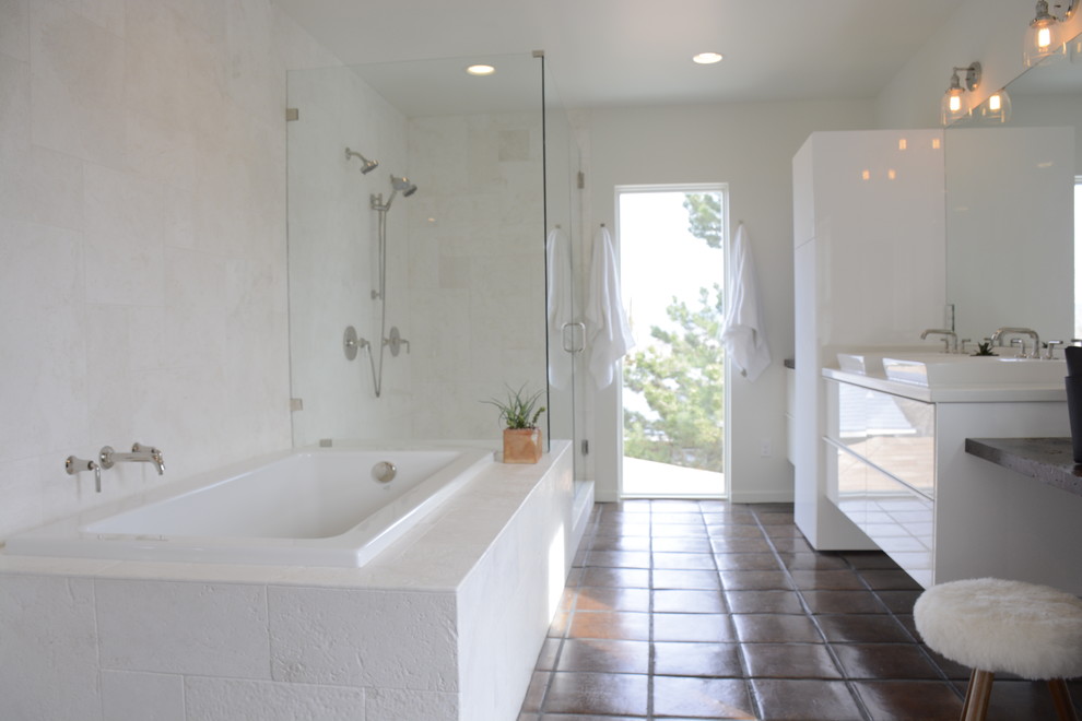 Photo of a mid-sized modern master bathroom in Other with flat-panel cabinets, white cabinets, a drop-in tub, a corner shower, white tile, subway tile, white walls, terra-cotta floors, a vessel sink and marble benchtops.