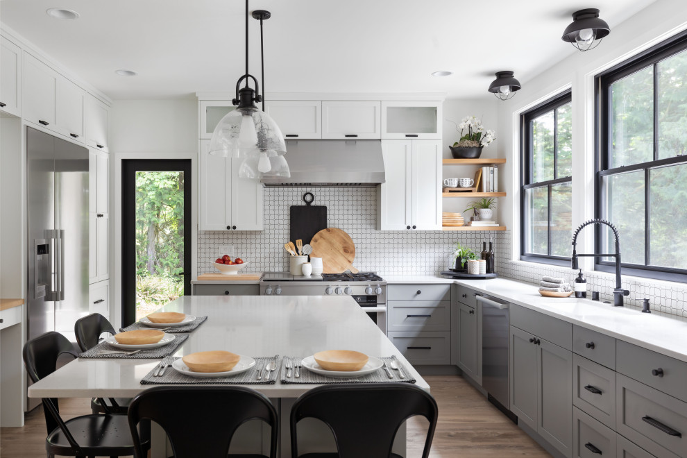 Large transitional open concept and l-shaped light wood floor kitchen photo in Seattle with white walls, a standard fireplace, a concrete fireplace, no tv, an island, quartz countertops, stainless steel appliances, a single-bowl sink, shaker cabinets, gray cabinets, white backsplash and white countertops
