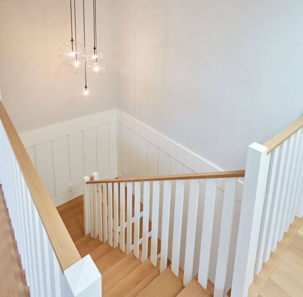 На фото: угловая лестница в классическом стиле с деревянными ступенями и панелями на части стены с