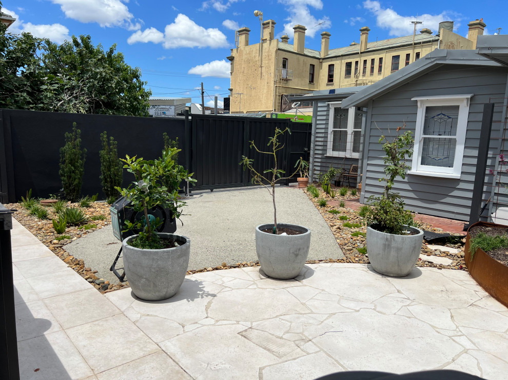 Foto di un piccolo giardino vittoriano esposto in pieno sole dietro casa in estate con un ingresso o sentiero, pavimentazioni in pietra naturale e recinzione in metallo
