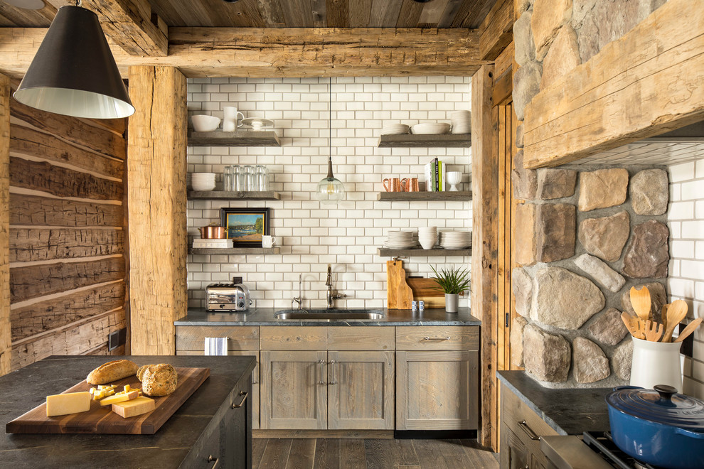 Inspiration for a large rustic u-shaped dark wood floor and brown floor eat-in kitchen remodel in Minneapolis with an undermount sink, shaker cabinets, medium tone wood cabinets, soapstone countertops, white backsplash, ceramic backsplash, paneled appliances and an island