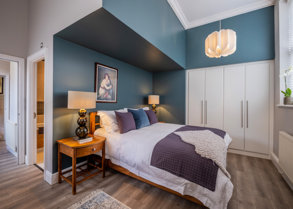 Mittelgroßes Eklektisches Hauptschlafzimmer mit blauer Wandfarbe, Laminat, braunem Boden und eingelassener Decke in Surrey