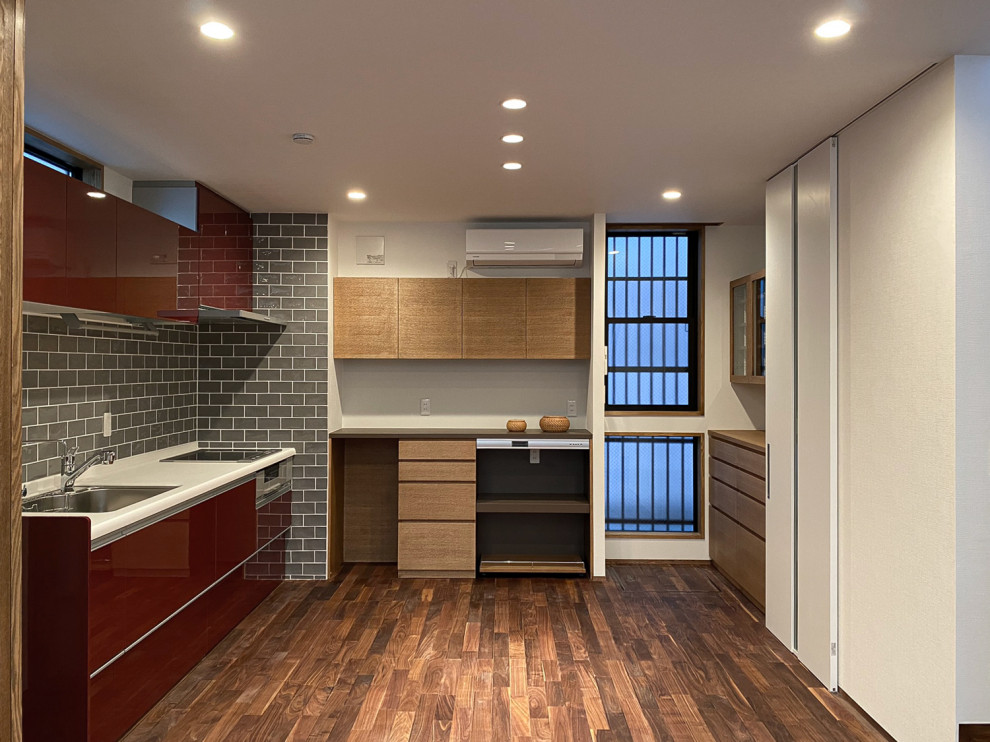 Eat-in kitchen - small single-wall dark wood floor, brown floor and wallpaper ceiling eat-in kitchen idea in Other with an undermount sink, beaded inset cabinets, red cabinets, solid surface countertops, gray backsplash, metal backsplash, stainless steel appliances and no island