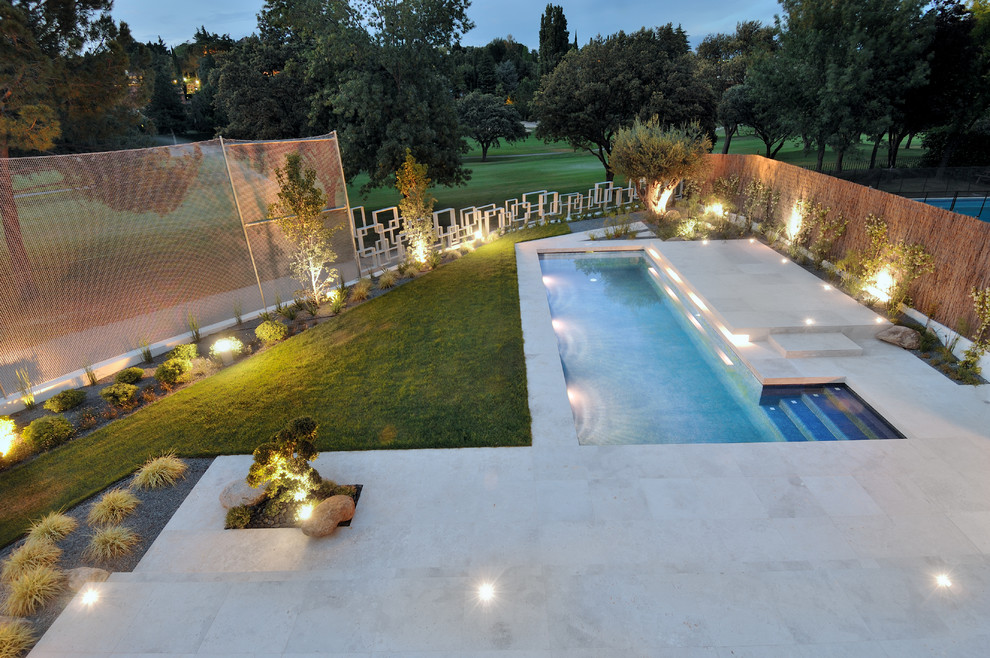 Design ideas for a mid-sized contemporary backyard rectangular lap pool in Madrid with a pool house.