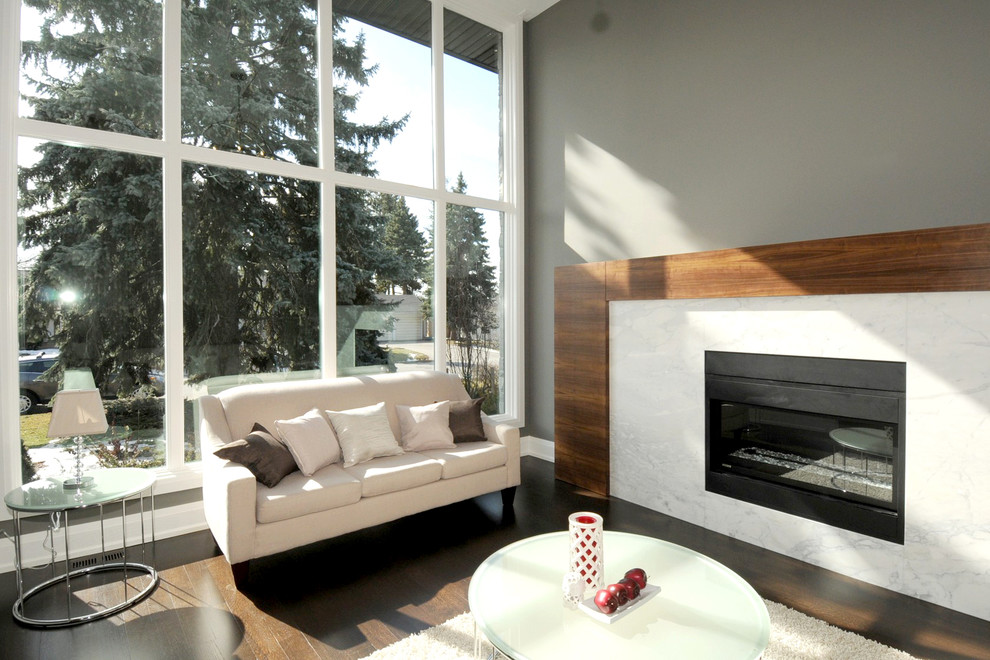 This is an example of a large modern formal enclosed living room in Toronto with no tv, grey walls, medium hardwood floors and a ribbon fireplace.