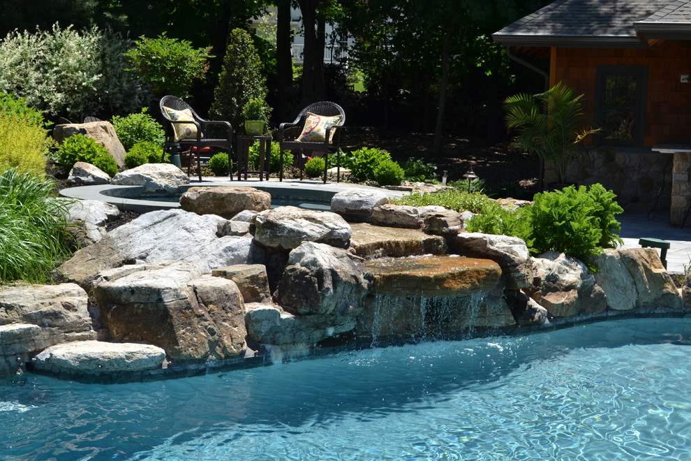 This is an example of a large modern backyard custom-shaped pool in New York with a water feature and concrete pavers.