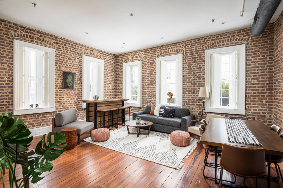 This is an example of an industrial living room in Charleston with brick walls.