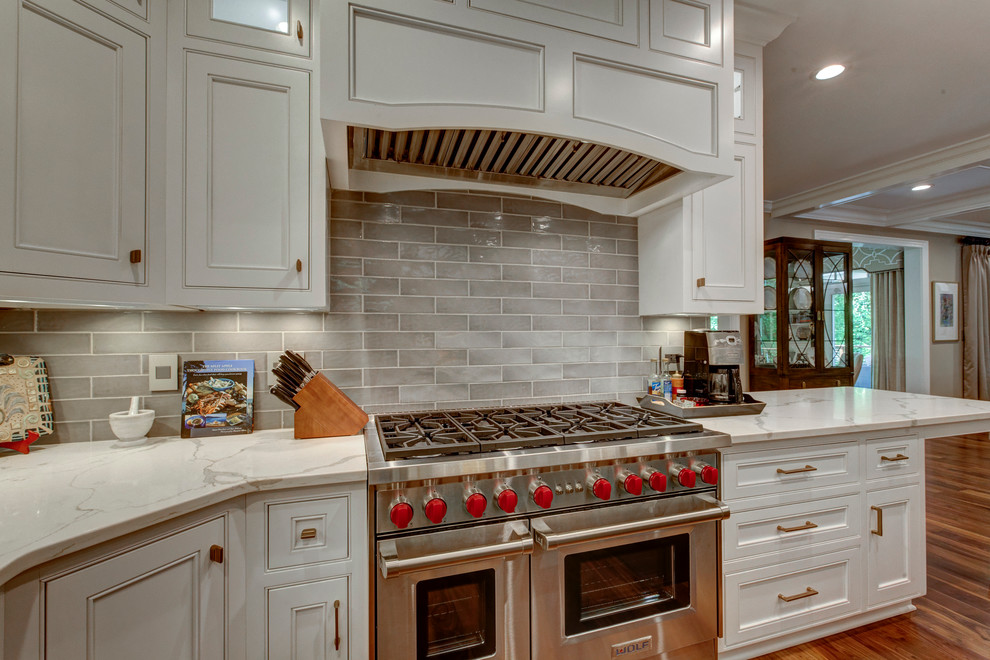 Inspiration for a large transitional u-shaped open plan kitchen in Raleigh with beaded inset cabinets, white cabinets, grey splashback, panelled appliances, dark hardwood floors, with island, a triple-bowl sink, marble benchtops and subway tile splashback.