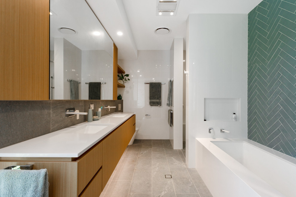 Photo of a contemporary master bathroom in Brisbane with light wood cabinets, an undermount tub, an alcove shower, a wall-mount toilet, gray tile, porcelain tile, grey walls, porcelain floors, an undermount sink, engineered quartz benchtops, grey floor, an open shower, white benchtops, a shower seat, a double vanity, a floating vanity and flat-panel cabinets.