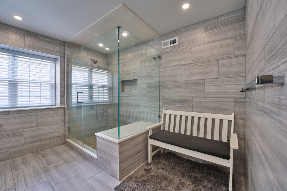 Inspiration for a medium sized modern ensuite bathroom in Philadelphia with grey tiles, grey walls, grey floors, a hinged door, a shower bench, flat-panel cabinets, grey cabinets, a two-piece toilet, ceramic tiles, lino flooring, a built-in sink, limestone worktops, white worktops, double sinks and a built in vanity unit.