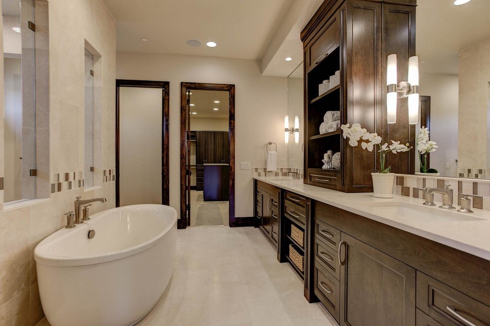 This is an example of an expansive mediterranean master bathroom in Denver with recessed-panel cabinets, dark wood cabinets, a freestanding tub, an alcove shower, beige tile, porcelain tile, beige walls, porcelain floors, an undermount sink, engineered quartz benchtops, beige floor, an open shower and beige benchtops.