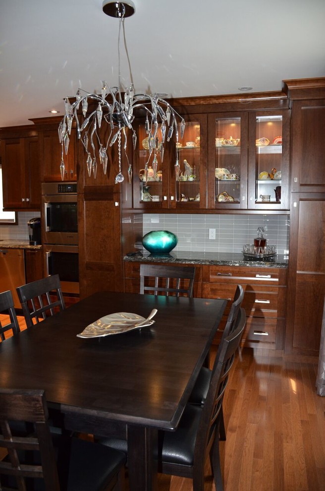 Open concept kitchen - large transitional l-shaped medium tone wood floor open concept kitchen idea in Toronto with an undermount sink, recessed-panel cabinets, dark wood cabinets, quartzite countertops, gray backsplash, glass tile backsplash, stainless steel appliances and an island