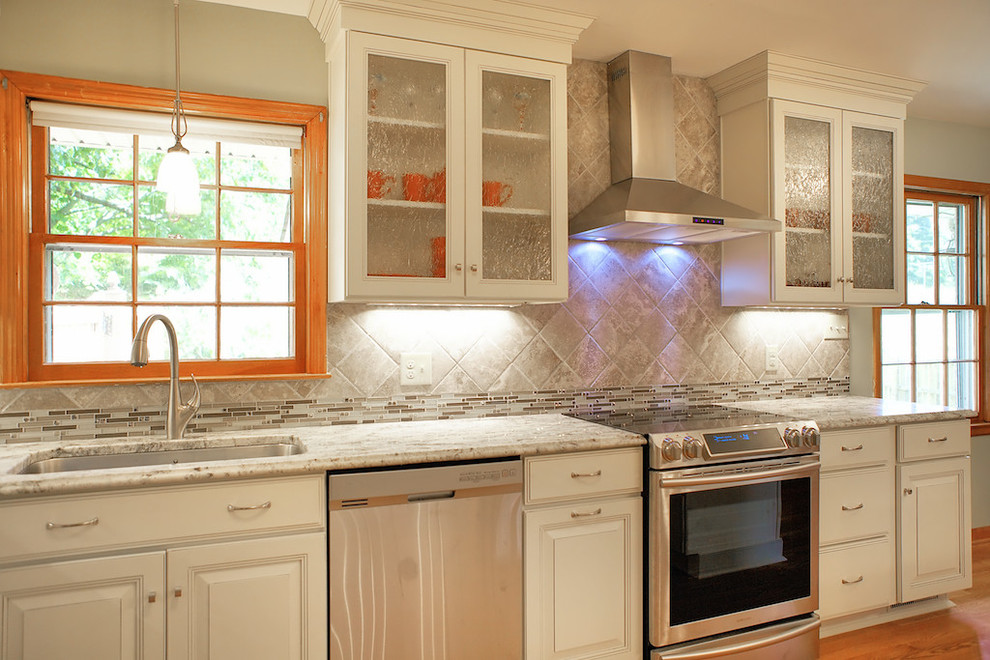Eat-in kitchen - large transitional u-shaped medium tone wood floor eat-in kitchen idea with raised-panel cabinets, white cabinets, granite countertops, gray backsplash, stainless steel appliances, yellow walls, a peninsula, a single-bowl sink and ceramic backsplash