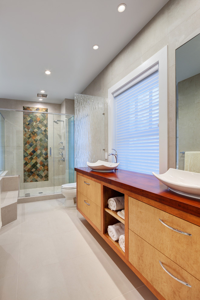 This is an example of a mid-sized contemporary master bathroom in Cleveland with a vessel sink, open cabinets, medium wood cabinets, wood benchtops, a corner tub, a shower/bathtub combo, a one-piece toilet, beige tile, porcelain tile, beige walls, porcelain floors, white floor and a hinged shower door.