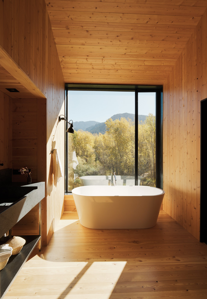 Foto di una stanza da bagno contemporanea con vasca freestanding e parquet chiaro