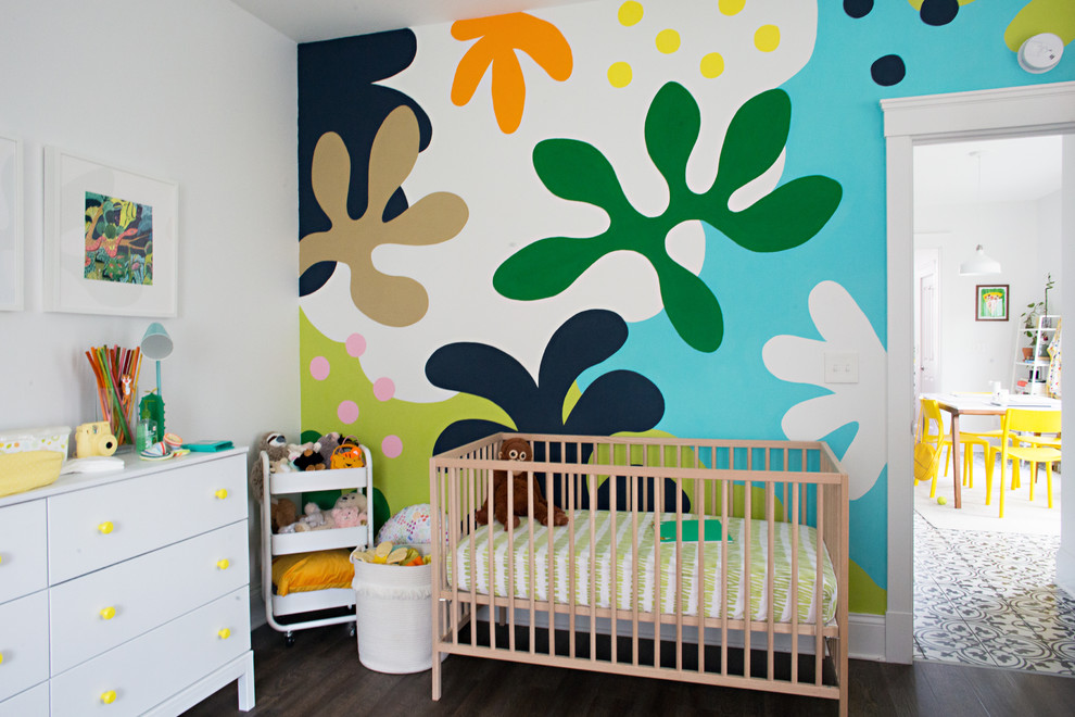 Eclectic gender-neutral nursery in Cincinnati with white walls, dark hardwood floors and brown floor.