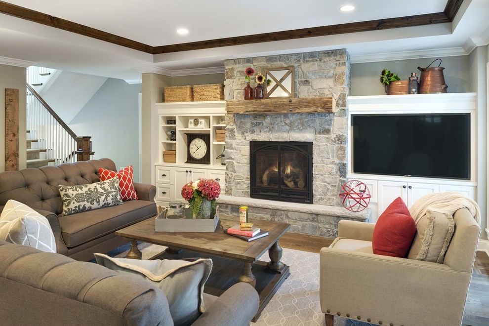 Design ideas for a mid-sized country enclosed family room in Minneapolis with grey walls, medium hardwood floors, a standard fireplace, a built-in media wall and brown floor.
