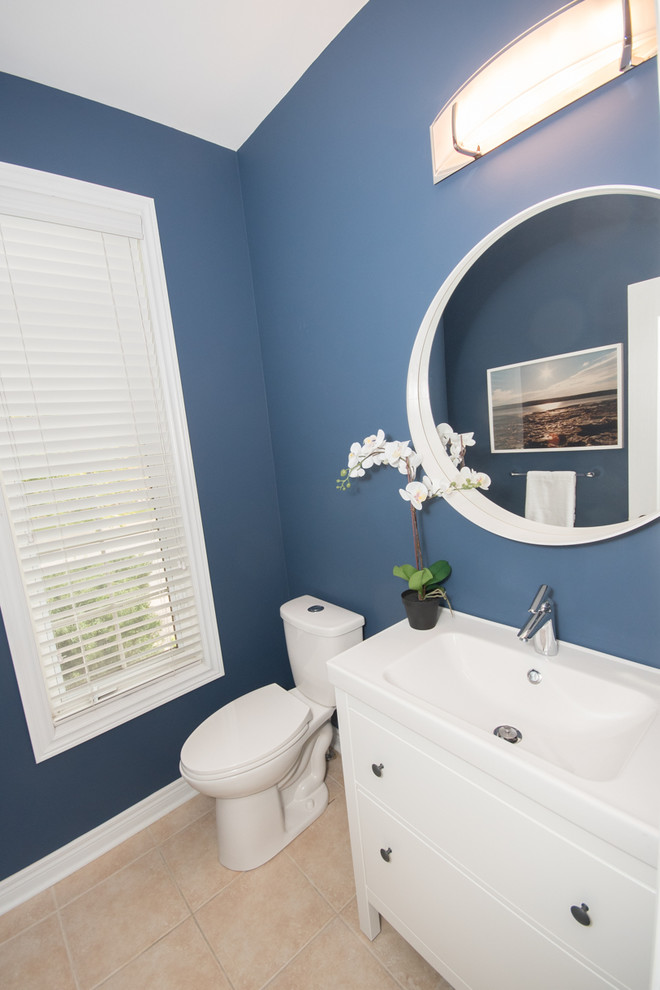 Photo of a mid-sized contemporary powder room in Toronto with shaker cabinets, white cabinets, a two-piece toilet, blue walls, porcelain floors, an integrated sink and beige floor.
