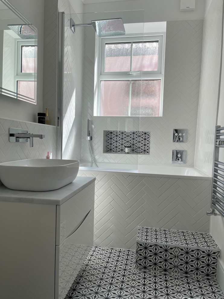 Exempel på ett mellanstort modernt grå grått badrum för barn, med släta luckor, vita skåp, ett japanskt badkar, en dusch/badkar-kombination, en vägghängd toalettstol, vit kakel, porslinskakel, vita väggar, klinkergolv i keramik, ett fristående handfat, bänkskiva i kvartsit, svart golv och dusch med gångjärnsdörr