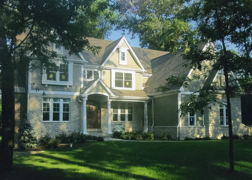 Photo of a mid-sized traditional two-storey green exterior in Chicago with stone veneer.