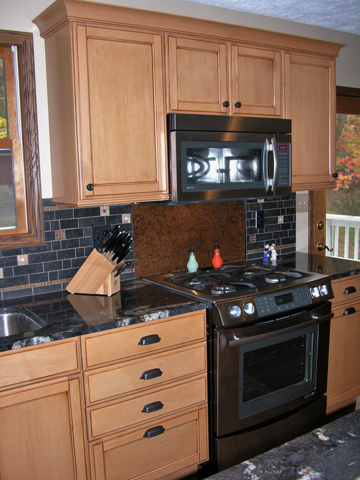 Inspiration for an eclectic medium tone wood floor kitchen remodel with an undermount sink, shaker cabinets, light wood cabinets, granite countertops, black backsplash, metal backsplash and stainless steel appliances