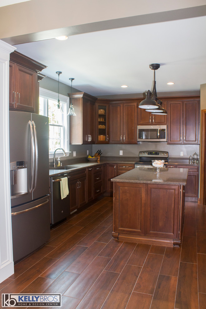This is an example of a medium sized traditional l-shaped kitchen/diner in Cincinnati with flat-panel cabinets, medium wood cabinets, engineered stone countertops, medium hardwood flooring, a submerged sink, stainless steel appliances and an island.