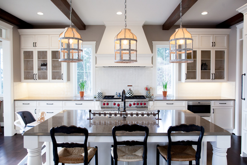 This is an example of a large country l-shaped open plan kitchen in Seattle with a farmhouse sink, shaker cabinets, white cabinets, granite benchtops, white splashback, ceramic splashback, stainless steel appliances, dark hardwood floors, with island and brown floor.