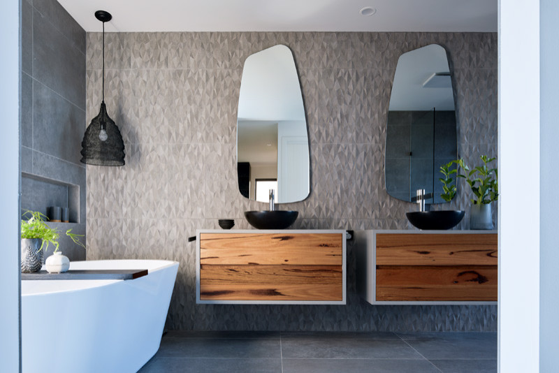 Design ideas for a large contemporary master bathroom in Melbourne with flat-panel cabinets, medium wood cabinets, a freestanding tub, solid surface benchtops, grey benchtops, a double vanity, a floating vanity, gray tile, ceramic tile, porcelain floors and grey floor.