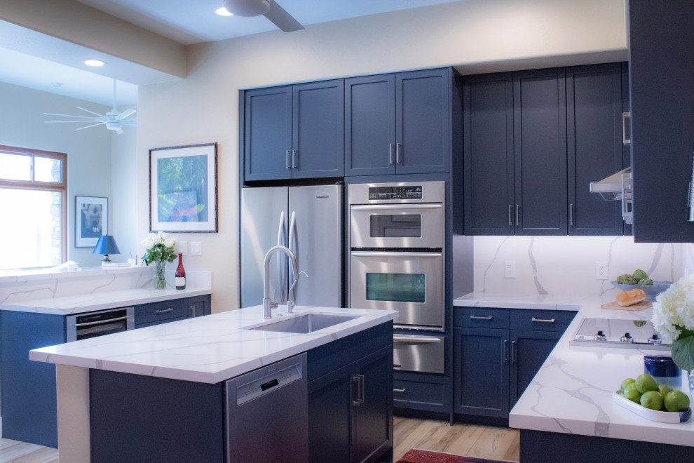 Example of a mid-sized transitional eat-in kitchen design in Phoenix with an undermount sink, shaker cabinets, blue cabinets, quartz countertops, white backsplash, quartz backsplash, stainless steel appliances, an island and white countertops